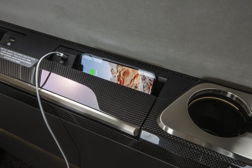 A charging smartphone and a usb charging cable onboard a private jet with a black and white interior