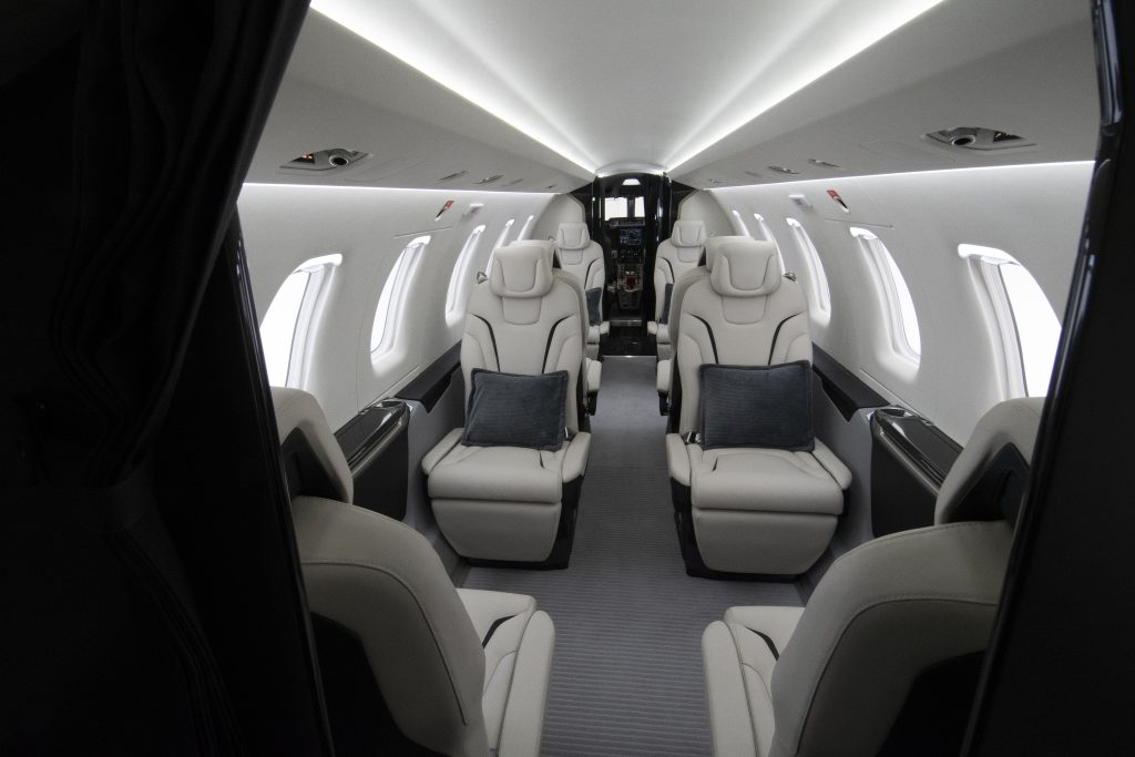 De binnenkant van een privéjet in een witte en grijze afwerking en lichtgrijze stoelen