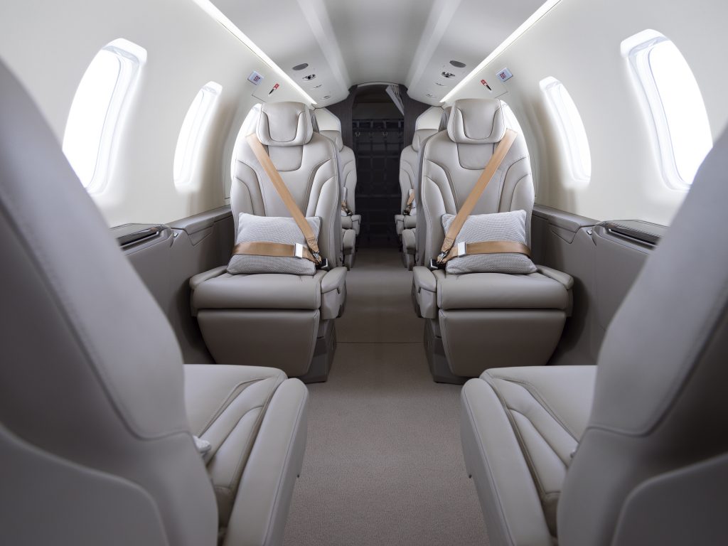 the inside of a private airplane in a white and grey finish and light grey seats