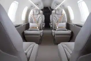 the inside of a private airplane in a white and grey finish and light grey seats