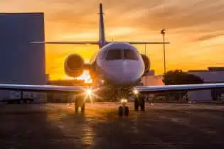 a white private jet on the ground during sunset