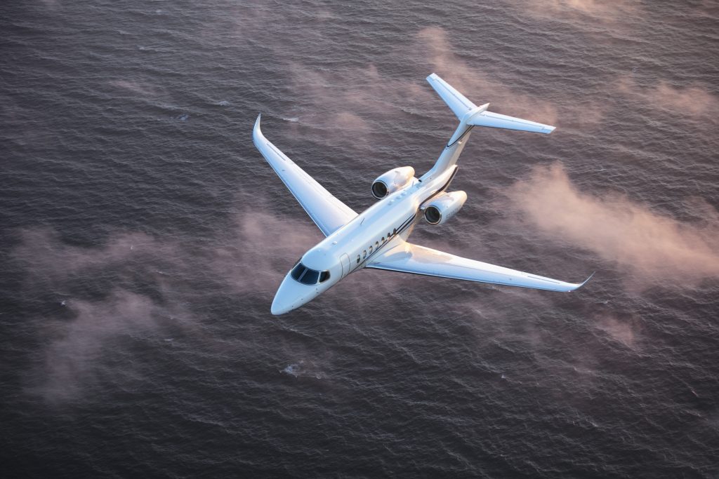 Private jet types: a white private midsize jet flying over sea