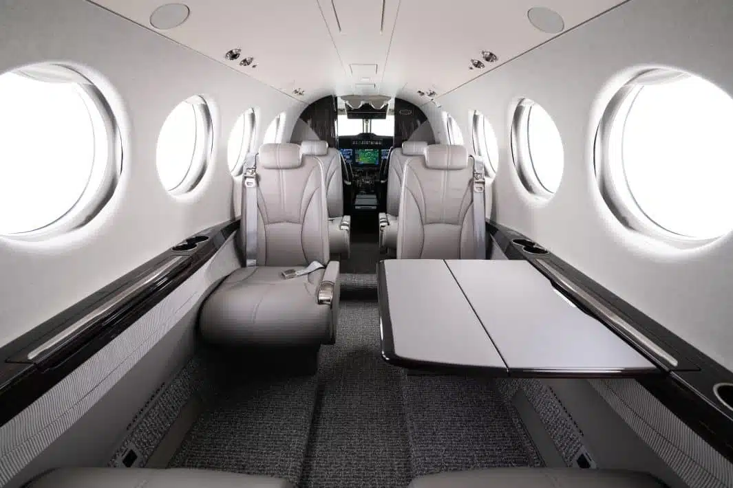The interior of a private jet with dark grey and black finish and white leather seats