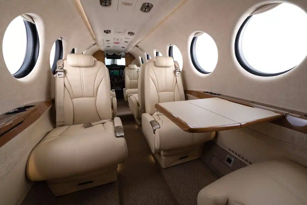 The interior of a private jet with a beige and brown finish and beige leather seats