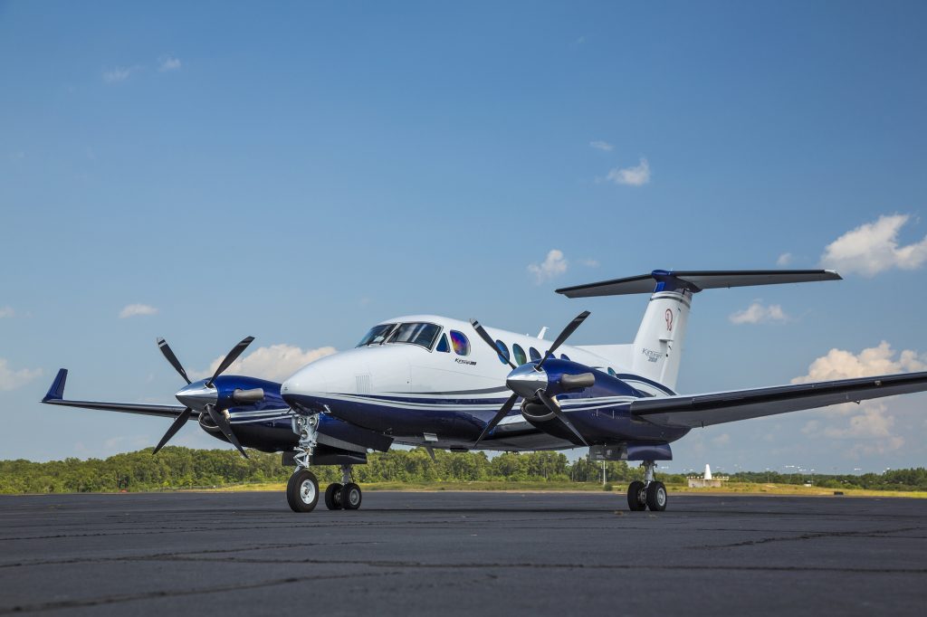 Turboprop private jet type: an executive white and blue painted turboprop airplane with two engines parked on the airport