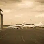 a picture in sepia style showing multiple private jet charter aircraft parked on the asphalt next to a hangar at the airport
