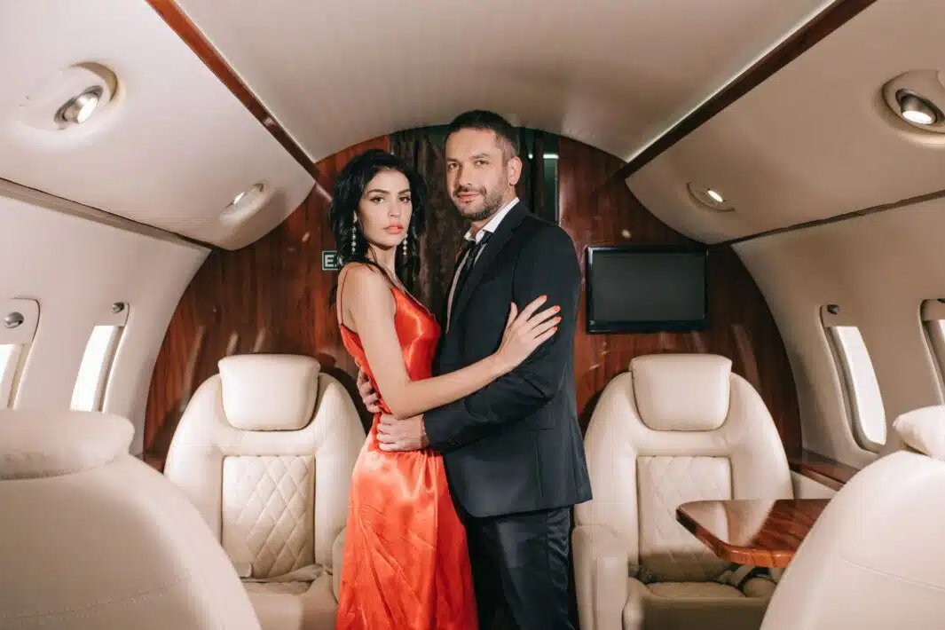 attractive woman in red dress standing with handsome bearded man in private jet