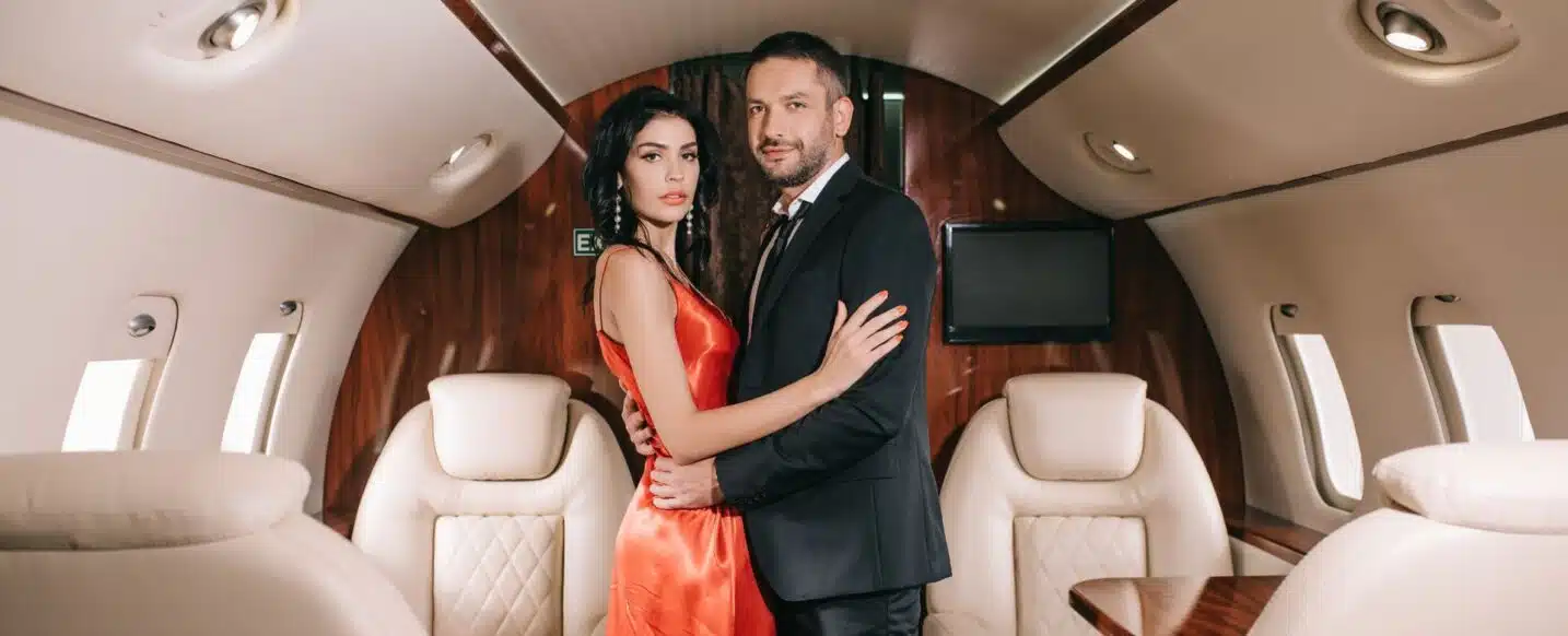 attractive woman in red dress standing with handsome bearded man in private jet