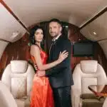 attractive woman in red dress standing with handsome bearded man in private jet