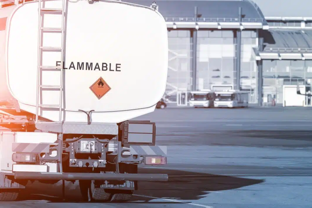 Back view small modern fuel tanker truck driving on airfield taxiway for aircraft refueling. Cistern lorry aviation gasoline. Plane gas supply. Airport maintenance handling service vehicle equipment