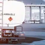 Back view small modern fuel tanker truck driving on airfield taxiway for aircraft refueling. Cistern lorry aviation gasoline. Plane gas supply. Airport maintenance handling service vehicle equipment