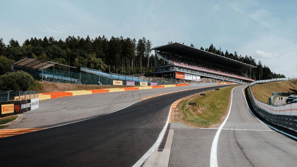 Lege grijze asfaltwegen onder een blauwe lucht met op de achtergrond een tribune op het Formule 1-circuit Spa-Francorchamps in België