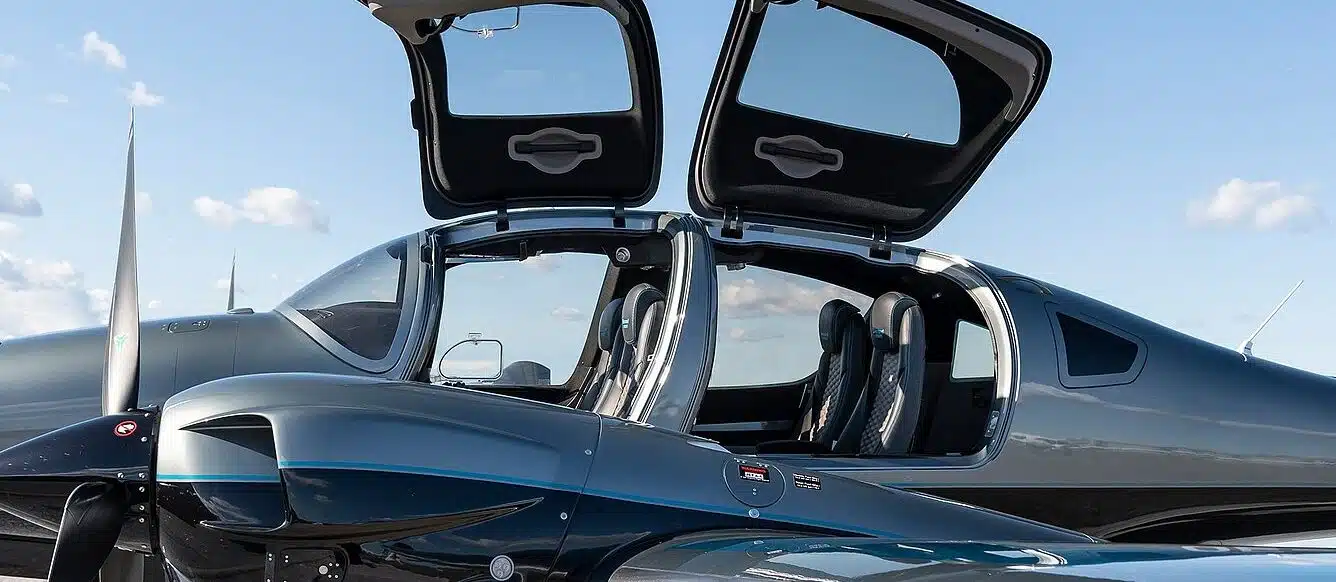 exterior close-up picture of a diamond da62 aircraft with business seating configuration and two open doors. the sky is clear with a few visible clouds.