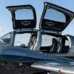 exterior close-up picture of a diamond da62 aircraft with business seating configuration and two open doors. the sky is clear with a few visible clouds.