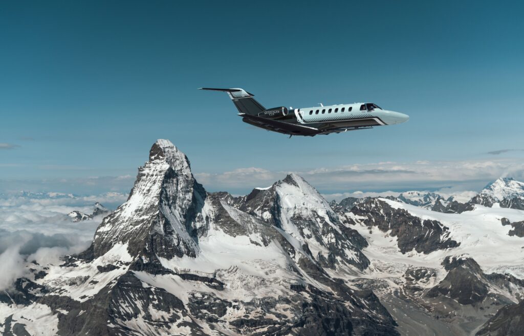 Exterior view of a Cessna CJ3 in flight, showing its sleek fuselage and T-tail design against a clear blue sky.