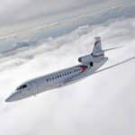 An all-white Dassault Falcon 8X business jet soaring above a thick cloud layer; showcasing long-range performance and sleek aerodynamic design.