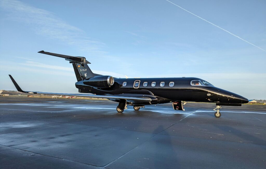 Black private jet parked on runway with door open for boarding.