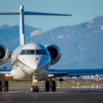 White private jet taxiing on the runway.