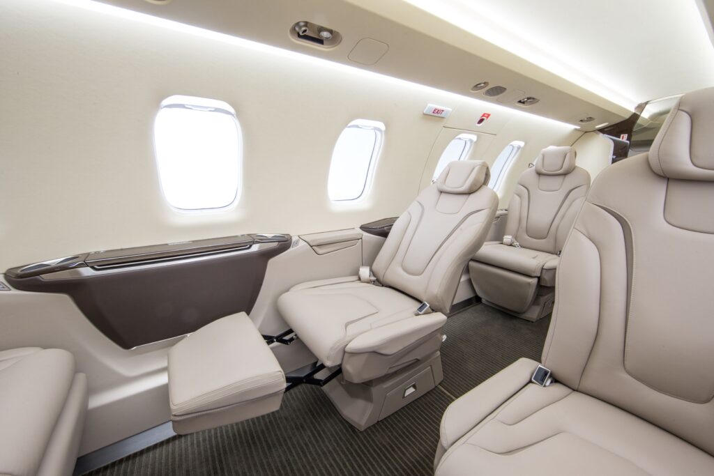 Interior of a Pilatus PC-24 with white leather seats in a reclined position.